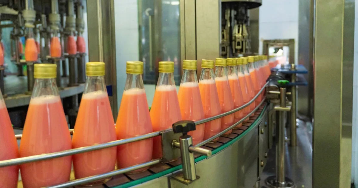Beverage bottling production line with glass bottles filled with fruit juice